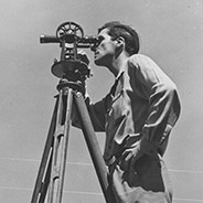 a man looking through a theodilite, a surveying instrument