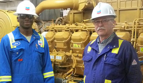 Two Chevron employees standing beside a dual fuel engine