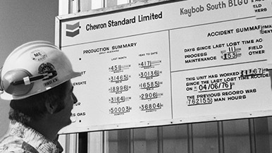Chevron employee in 1960's looking at Kaybob well sign