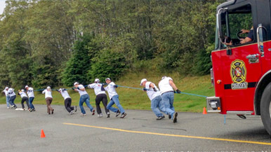Chevron employees pulling a fire truck for charity