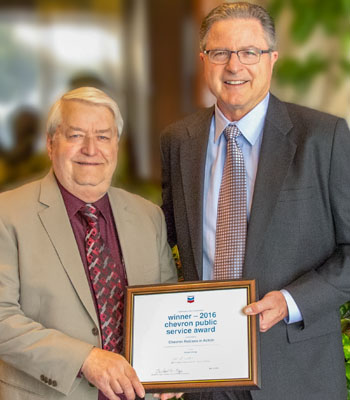 Harold Freund, president of the Canadian Prairie Chapter of the Chevron Retirees Association (left), accepts the 2016 Chevron Public Service Award from Chevron Corporation Chairman and CEO John Watson.