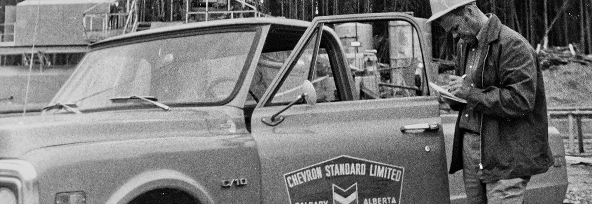 Chevron employee reading a document beside a truck in the 1950's