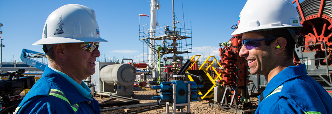Two Chevron employees talking at a drilling site in Alberta
