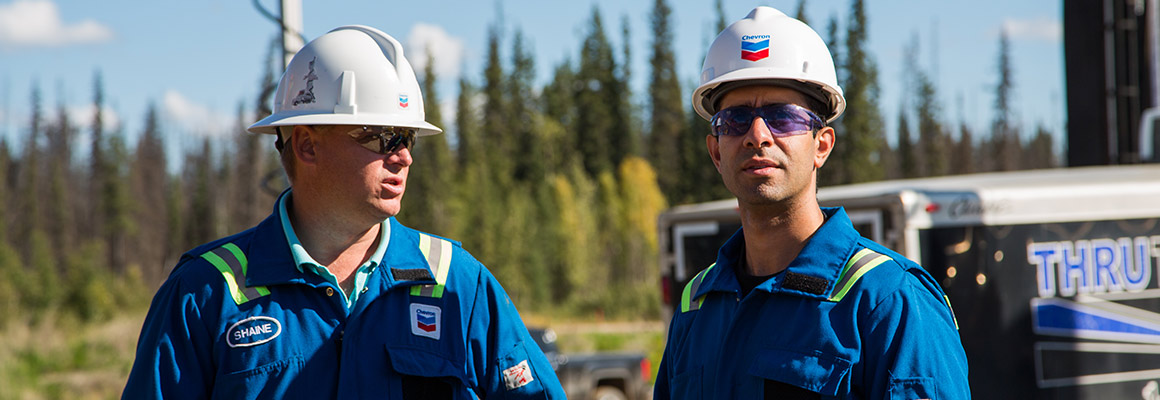 Two Chevron employees standing near a generator