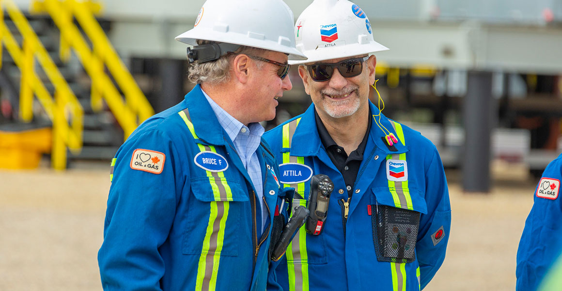 Two Chevron employees speaking at a Kaybob Duvernay production site