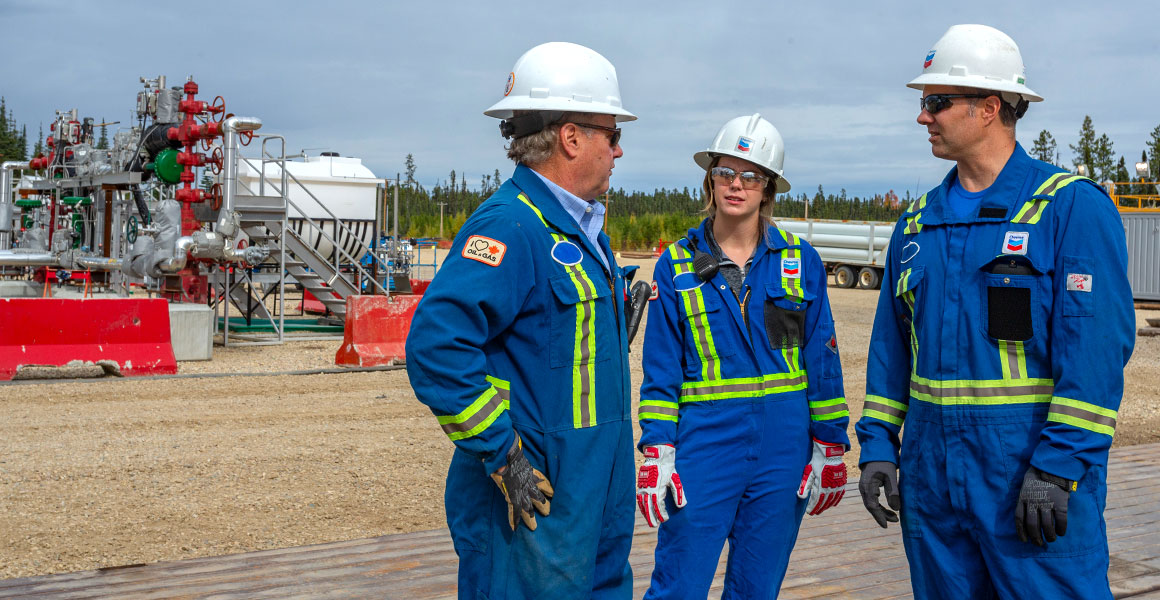Three Chevron employees talking at a production facility in Alberta.