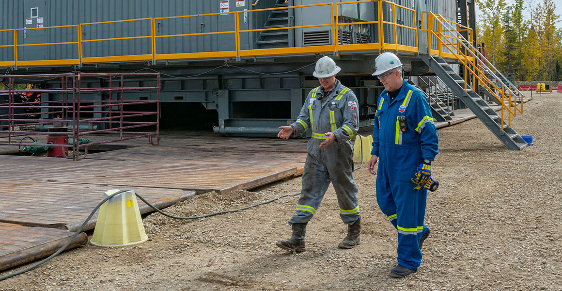 Chevron employee and contractor talking at a drilling site in Alberta
