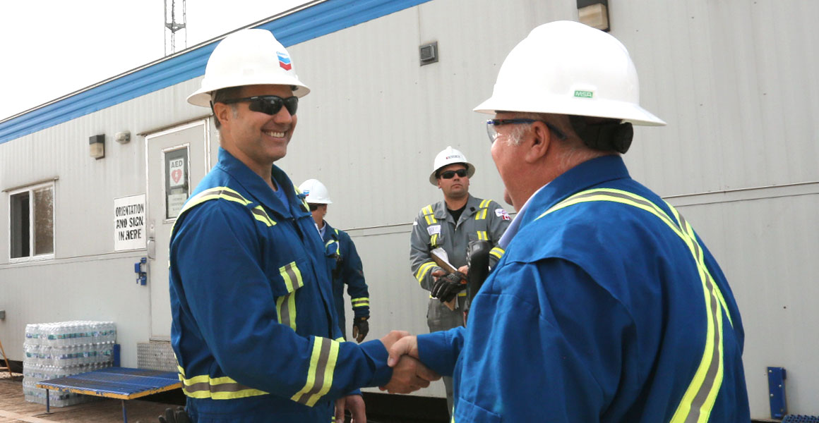 People shaking hands and smiling at a Chevron site in Alberta
